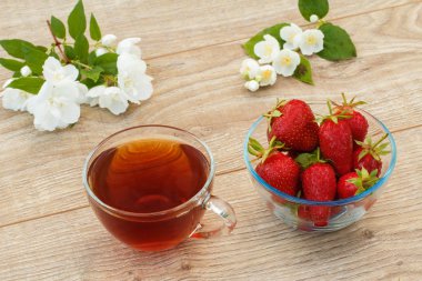 Beyaz yasemin çiçekli ve çilekli bir bardak çay..