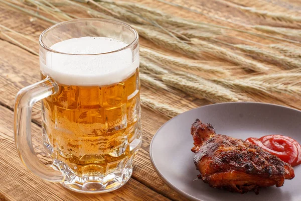 Sklenice piva, talíř s grilovaným kuřetem a ušima ječmene na dřevěném pozadí. — Stock fotografie