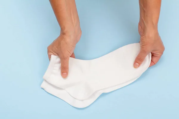 Manos femeninas con calcetines de mujer sobre fondo azul . — Foto de Stock