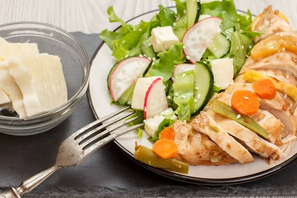 Piatto con carne, insalata di verdure con formaggio, cetriolo e ravanello su tavola di pietra . — Foto Stock