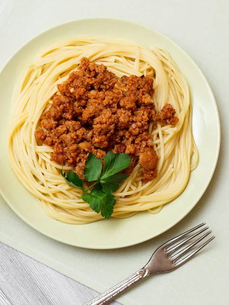 Espaguetis boloñeses en un plato con tenedor de metal . —  Fotos de Stock