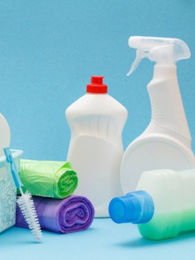 Bulaşık deterjanı şişeleri, çöp torbaları ve mavi arka planda fırça..
