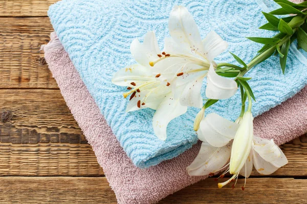 Zachte badstof handdoeken met boeket bloemen op houten achtergrond. — Stockfoto