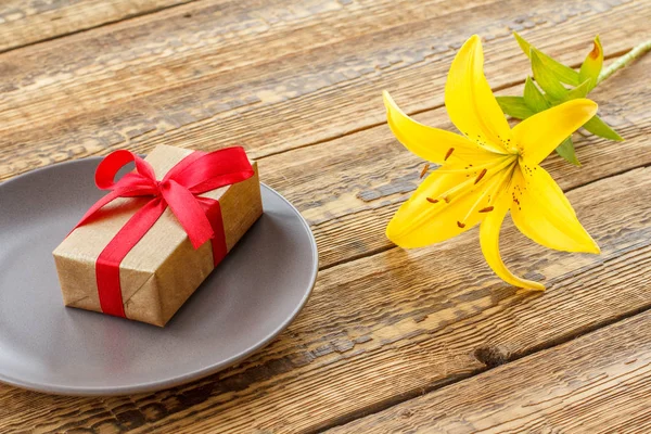 Подарочная коробка с цветком лилии на деревянном фоне . — стоковое фото