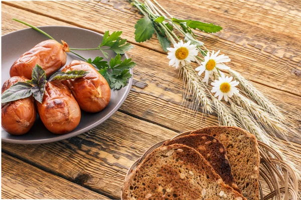 Grilled sausages on plate and toasts on wooden boards — Stock Photo, Image