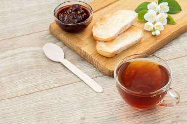 Bir bardak çay, ekmek, çilek reçeli ve beyaz yasemin çiçekleri.