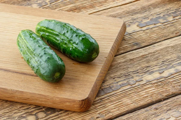 Just picked cucumbers lying on cutting board. — Stock Photo, Image