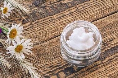 Kozmetik krem ve ahşap arka planda taze papatya çiçeği..