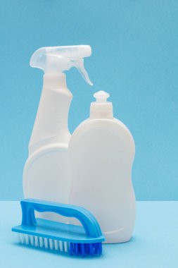 Mavi arka planda bulaşık sıvısı ve fırça şişeleri.
