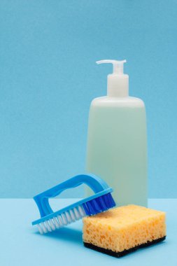 Bir şişe bulaşık suyu ve mavi arka planda fırça..