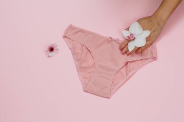 Pembe arka planda güzel külotlu bir kadın eli..