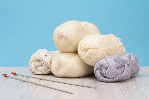 Woolen yarn for knitting. Balls of natural wool yarn and knitting needles