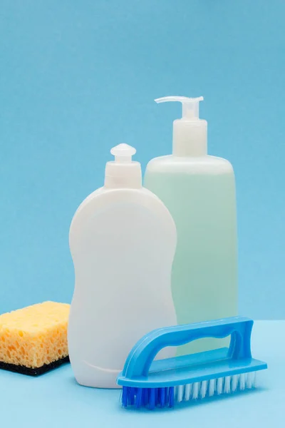 Botellas de líquido lavavajillas, esponja y cepillo sobre fondo azul . —  Fotos de Stock