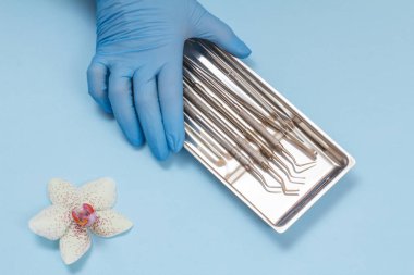 Diş bakımı için metal diş aletleri seti olan bir dişçi eli.