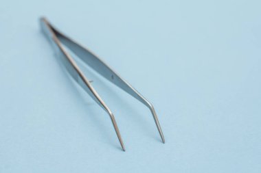 Tweezers on blue background. Metal medical instruments.