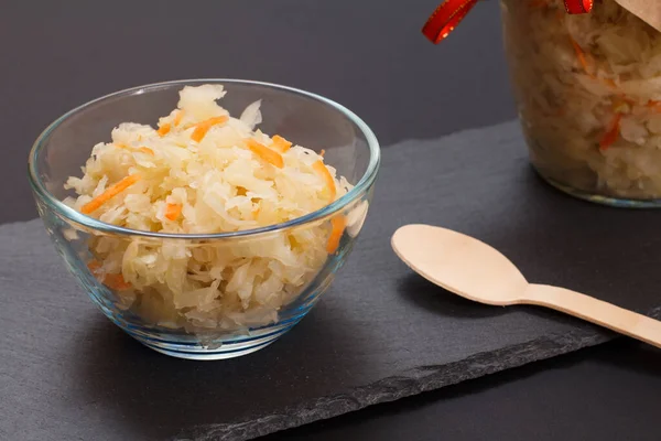 Fermented cabbage with herbs and spices in glass bowl on the black background — Stock Photo, Image