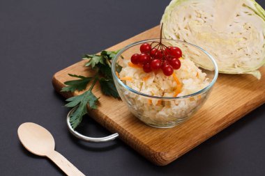 Siyah arka planda cam kasede otlar ve baharatlarla mayalanmış lahana.