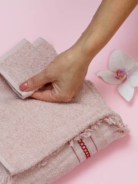 Мягкое махровое полотенце с рукой на розовом фоне . — стоковое фото