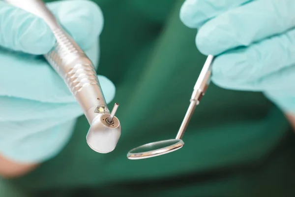 Les mains du dentiste en gant avec pièce à main dentaire et miroir buccal . — Photo