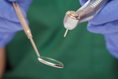 Diş fırçası ve ağız aynası olan eldivenli dişçi elleri..