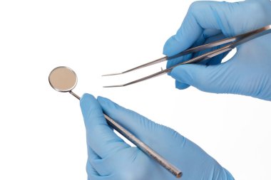 Cımbız ve ağız aynası olan dişçi elleri..