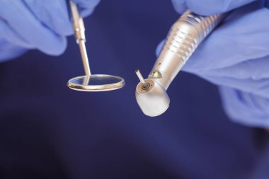 Diş fırçası ve ağız aynası olan eldivenli dişçi elleri..