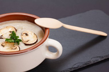 Siyah arka planda porselen kasede mantarlı krema çorbası..