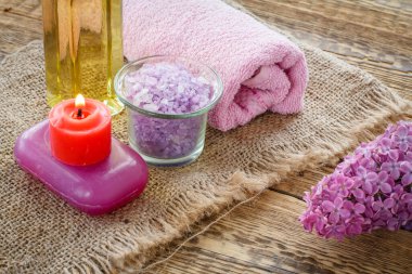 Deniz tuzu, sabun, yanan mum, bir şişe yağ, leylak çiçekleri ve tuvalet işlemleri için tahta tahta tahtalar. Spa ürünleri ve aksesuarlar. Üst görünüm.