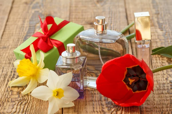 Pudełko Czerwoną Wstążką Butelkami Perfum Drewnianych Deskach Bukietem Czerwonych Tulipanów — Zdjęcie stockowe