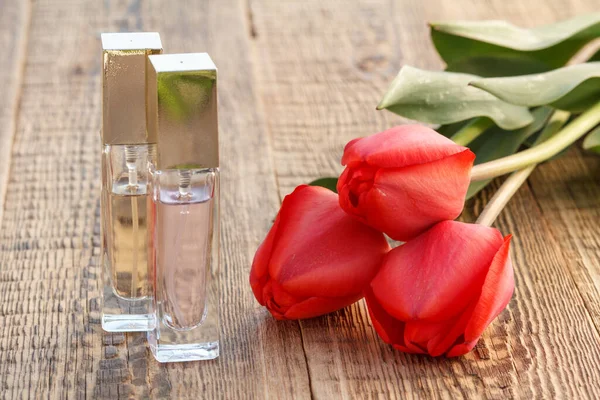 Butelki Perfum Czerwonych Tulipanów Drewnianych Deskach — Zdjęcie stockowe