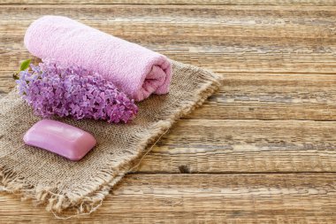 Çuval bez ve tahta tahtalarda banyo prosedürleri için leylak çiçeği, sabun ve havlu. Spa ürünleri ve aksesuarlar. Üst görünüm.