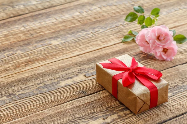 Подарочная Коробка Завернутая Красной Лентой Старых Деревянных Досках Украшенных Розами — стоковое фото