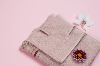 Kırmızı paskalya ve pembe arka planda beyaz orkide tomurcukları olan yumuşak terry havlusu. Üst görünüm.