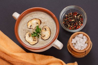 Lezzetli ev yapımı mantar kremalı çorba dilimlenmiş mantarlı porselen kâse, tüm baharatlar ve siyah taş tahtada tuz bulunan küçük tahta fıçı. Üst görünüm.