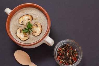 Porselen bir kasede dilimlenmiş mantar mantarlı krema çorbası, tüm baharatlar ve siyah arka planda ahşap kaşık. Üst görünüm.