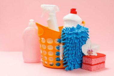 Plastik sepette bulaşık deterjanı, cam ve fayans temizleyici mikrodalga fırınlar ve fırınlar için deterjan, mavi arka planda bez ve süngerler. Yıkama ve temizleme seti.