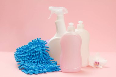 Plastik bulaşık deterjanı, cam ve fayans temizleyicisi mikrodalga fırın ve fırınlar için deterjan pembe arka planda bir bez ve beyaz orkide çiçeği. Yıkama ve temizleme seti.