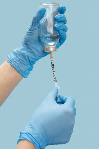ガラス瓶と注射器を保持ラテックス手袋で医師の手のクローズアップビューと青い背景に注射用の液体薬を拾う 健康と医療の概念 — ストック写真