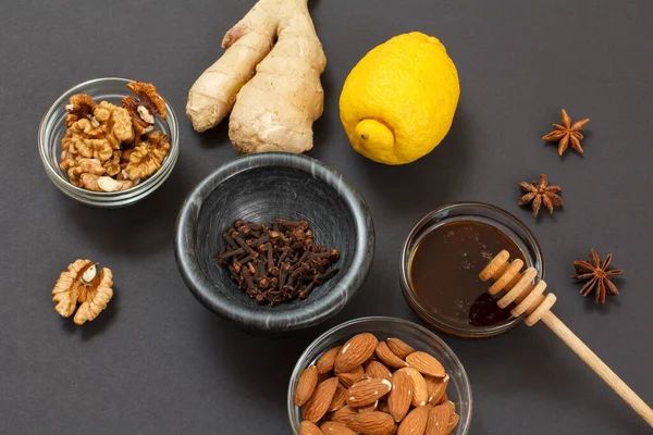 Health remedy foods for cold and flu relief with lemon, ginger, honey and walnuts on a black background. Top view. Foods That Boost the Immune System.