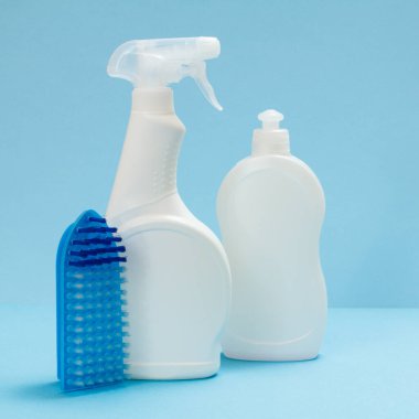 Plastik bulaşık deterjanı, cam ve fayans temizleyici ve mavi arka planda bir fırça. Yıkama ve temizleme seti.