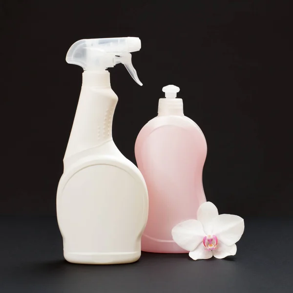 Πλαστικά Μπουκάλια Υγρού Πλύσης Πιάτων Και Ένα Λευκό Λουλούδι Ορχιδέας — Φωτογραφία Αρχείου