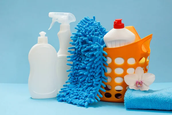 Plastic basket with bottle of dishwashing liquid, a rag and sponges on blue background. Washing and cleaning set.