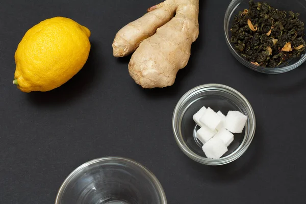 Health remedy foods for cold and flu relief with lemon, ginger and green tea on a black background. Top view. Foods That Boost the Immune System.