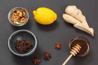 Soğuk algınlığı için sağlıklı besinler ve siyah arka planda limon, zencefil, bal ve ceviz içeren grip ilacı. Üst Manzara. Bağışıklık sistemini güçlendiren gıdalar.