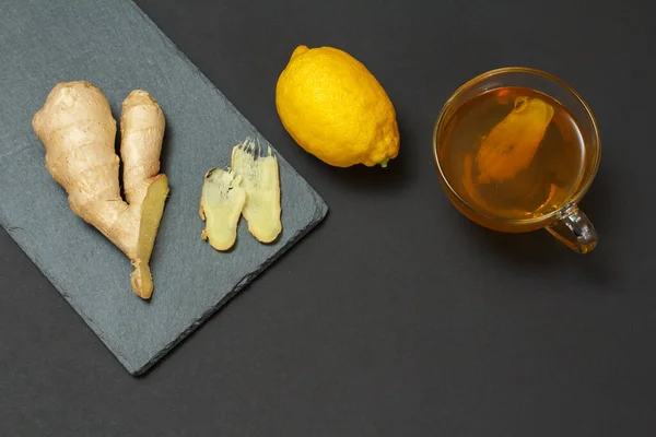 Health remedy foods for cold and flu relief with lemon, ginger and tea on a black background. Top view. Foods That Boost the Immune System.
