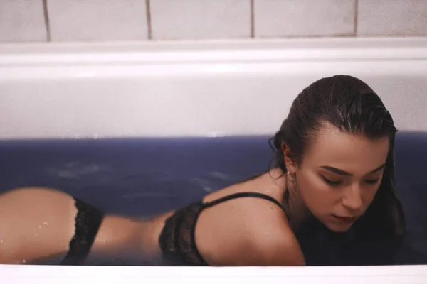 Chica en la bañera con agua azul. chica en lencería con el pelo mojado. retrato de una mujer con grandes ojos . —  Fotos de Stock