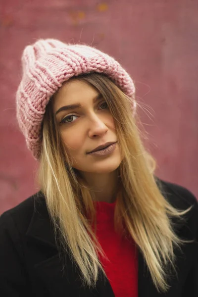 Menina loira com olhos grandes e lábios gordos contra um fundo rosa. mulher em volumoso chapéu de pó de cor quente . — Fotografia de Stock