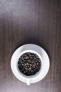 ahşap arka plan üzerinde beyaz fincan kahve çekirdeği.
