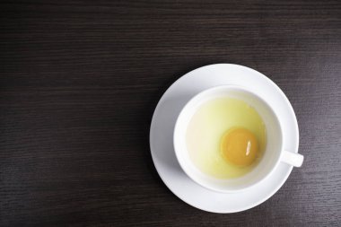 Ahşap arka plan üzerinde beyaz fincan taze yumurta.