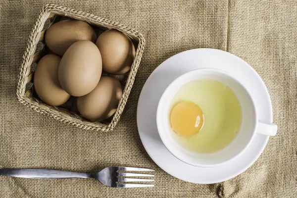 Bez arka plan üzerinde beyaz fincan taze yumurta.